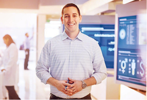 Un homme souriant se tient debout devant de grands écrans montrant les solutions fondées sur les données d'Express Scripts Canada.