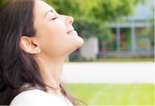 A young woman with her face turned to the sun with her eyes closed enjoying the health benefits of being an Express Scripts Canada member