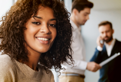 A smiling young black female sitting in front of standing clients 