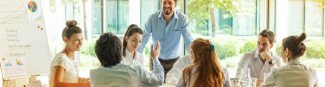 A group of professionals at a meeting sitting around a boardroom table with  one man standing and leaning over while in conversation with a colleague at Express Scripts Canada