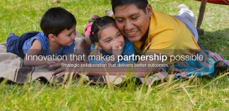 A healthy Indigenous father laying on a blanket on the grass with his two young children