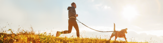 Image of an Express Scripts Canada member jogging with his dog and the ESC Raising Health logo on the left side